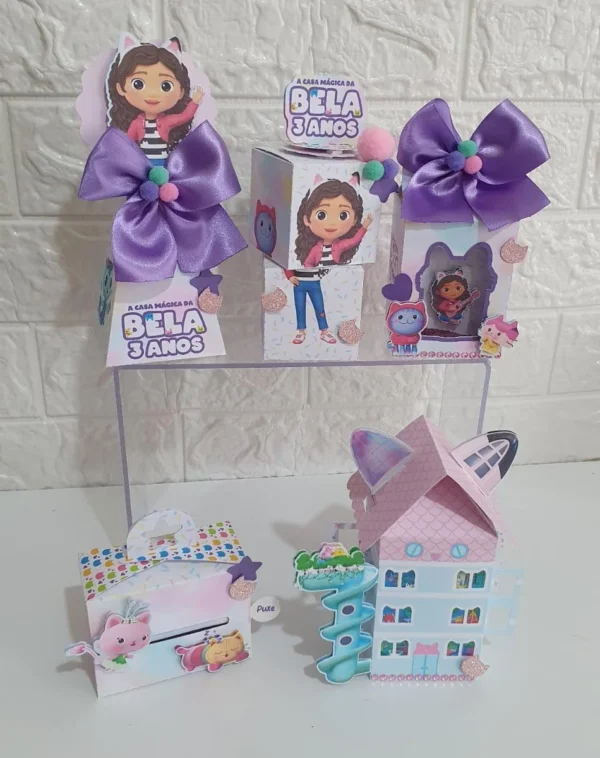 Topper de bolo festivo com a fachada da casa de bonecas com orelhas de gatinho e balões coloridos nas laterais, trazendo a personagem Gabby sorridente ao lado do Pandy Gato em camadas tridimensionais em arquivo digital de corte.