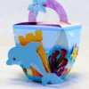 Molde de caixa milk rosa pastel com ilustrações aquareladas de algas marinhas e peixinhos, trazendo um aplique grande de concha do mar com pérola tridimensional na frente.