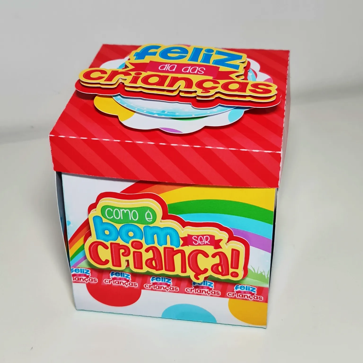Lembrancinha cartonada com formato de carrossel de parque de diversões, balões de gás coloridos flutuando na tampa vazada e moldura com silhuetas de crianças brincando em camadas tridimensionais em arquivo digital de corte.