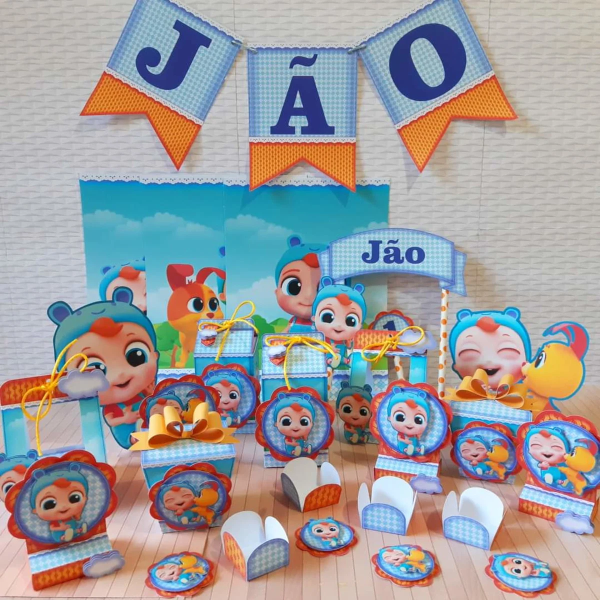 Topper de bolo infantil com o personagem Joãozinho do Little Angel sorrindo com os braços abertos, vestindo seu macacão azul clássico e cercado por notas musicais coloridas e nuvens brancas em camadas tridimensionais em arquivo digital de corte.
