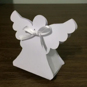 Embalagem caixinha vertical branca com recortes vazados nas laterais em formato de asas de anjo espelhadas, trazendo na frente um aplique de anjinho com auréola dourada brilhante e mãos postas em oração em camadas tridimensionais em arquivo digital de corte.