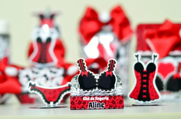 Elementos decorativos em camadas com espartilhos e corações para decoração de mesa de chá de lingerie.