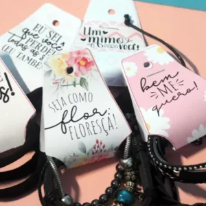 Tag de papel em formato de gravata com fundo rosa pastel e estampa de mini corações brancos, trazendo na parte frontal a frase "Um mimo para agradecer a sua preferência" escrita em letras cursivas e elegantes em arquivo digital.