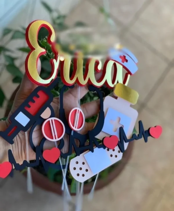 Topper de bolo temático com símbolos da área da saúde exibindo uma prancheta de prontuário, um estetoscópio cruzado, uma seringa realista e um chapéu tradicional de enfermeira, dispostos em camadas tridimensionais em arquivo digital de corte.