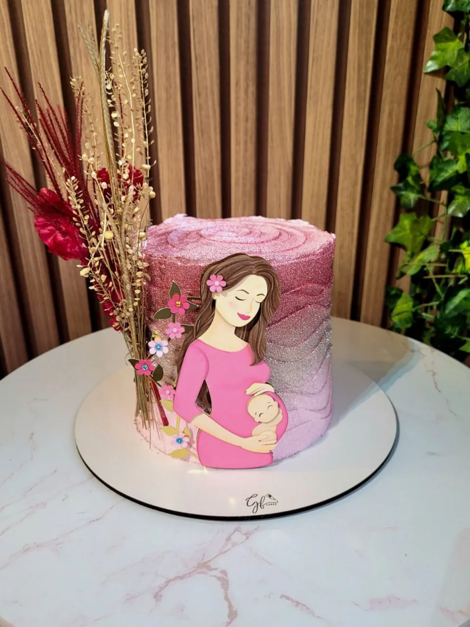 opper de bolo com a silhueta delicada de uma mãe grávida de perfil segurando a barriga, cercada por flores em tons pastéis de rosa e azul, ramos dourados espelhados e borboletas vazadas em camadas tridimensionais em arquivo digital de corte.