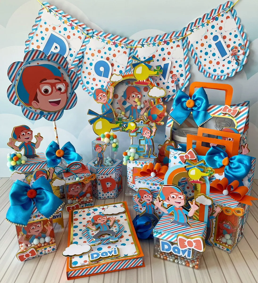 Embalagem milk vertical com estampa listrada em azul e laranja, trazendo na frente o personagem Blippi sorridente de óculos e gravata borboleta laranja em aplique tridimensional sobreposto em arquivo digital de corte.
