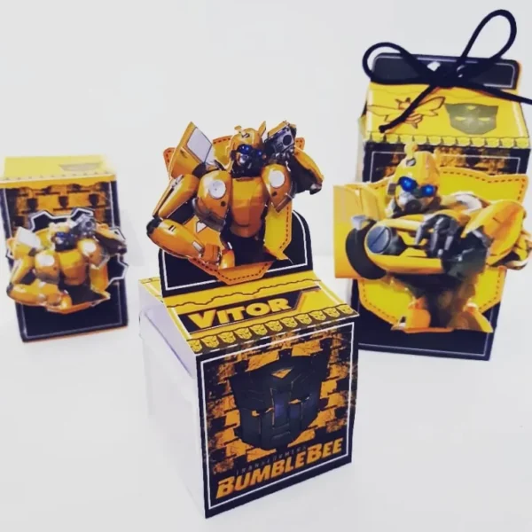 Molde digital de caixa maleta amarela com alça embutida, decorada com padrões de colmeia de abelha em tons pretos e o rosto do robô Bumblebee em destaque na lateral.