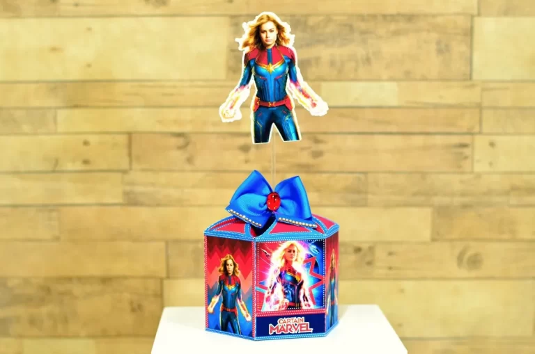 Arquivo de corte de caixa de papel sextavada com tampa piramidal, decorada com texturas de ficção científica e aplique da Capitã Marvel em pose de ação.