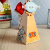 Arquivo de corte de caixinha quadrada de papel imitando a cabeça de um robô retrô, com antenas recortadas no topo e olhos de lâmpadas amarelas em relevo na frente.