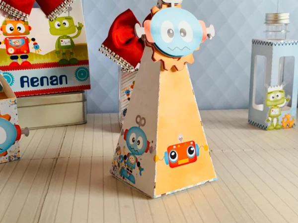 Arquivo de corte de caixinha quadrada de papel imitando a cabeça de um robô retrô, com antenas recortadas no topo e olhos de lâmpadas amarelas em relevo na frente.