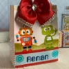 Elementos digitais para topo de bolo exibindo uma engrenagem gigante como fundo, um robô segurando uma placa de feliz aniversário e faixas para personalização.