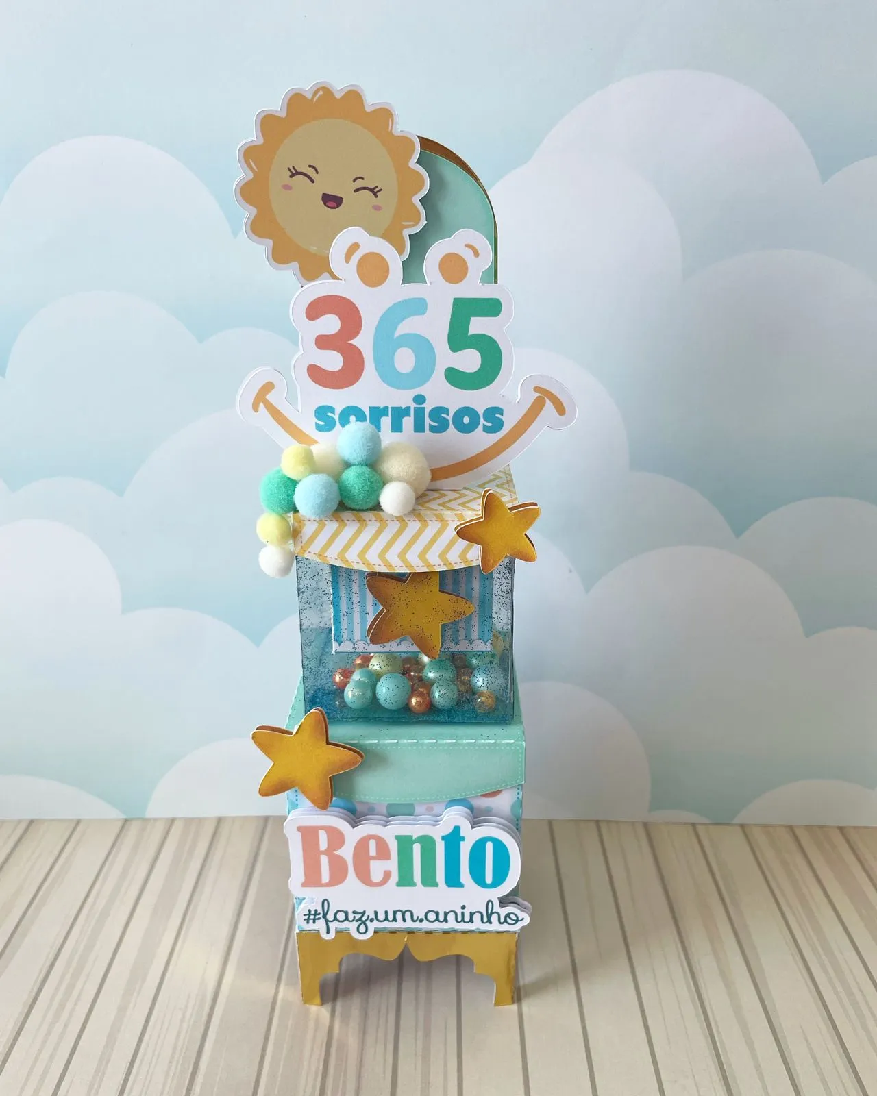 Centro de mesa com base sextavada vermelha, trazendo no topo o número 365 em papel laminado dourado, cercado por estrelas brilhantes vazadas e emojis sorridentes que parecem flutuar em camadas tridimensionais em arquivo digital de corte.