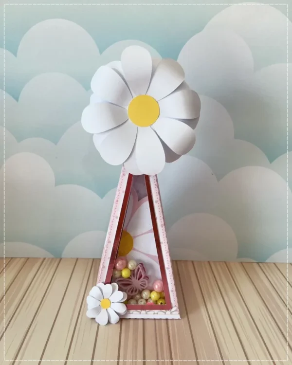 Centro de mesa com base sextavada amarela, trazendo no topo um arranjo denso de margaridas brancas tridimensionais e borboletas em papel perolado com asas vazadas que parecem flutuar sobre as flores em camadas tridimensionais em arquivo digital de corte.