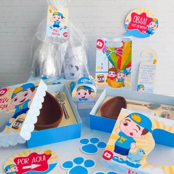 Topper de bolo com o personagem Luccas Neto em um cenário de Páscoa com cenouras e o icônico selo do aventureiro azul em camadas de papelaria personalizada.