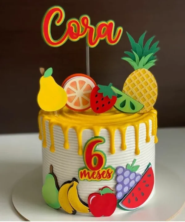 Topper de bolo infantil com o tema feirinha e frutas, exibindo apliques em camadas tridimensionais de melancia, morango, abacaxi e laranja sorridentes em estilo kawaii.