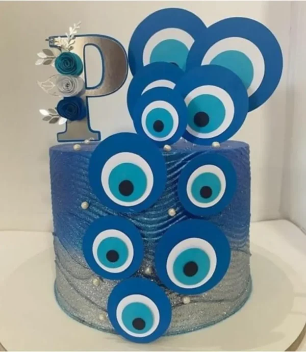 Elementos digitais para topo de bolo com o tema Olho Grego, exibindo mandalas circulares concêntricas nas cores azul-escuro, azul-claro e branco, com detalhes dourados em filigrana e ramos de folhas metálicas.