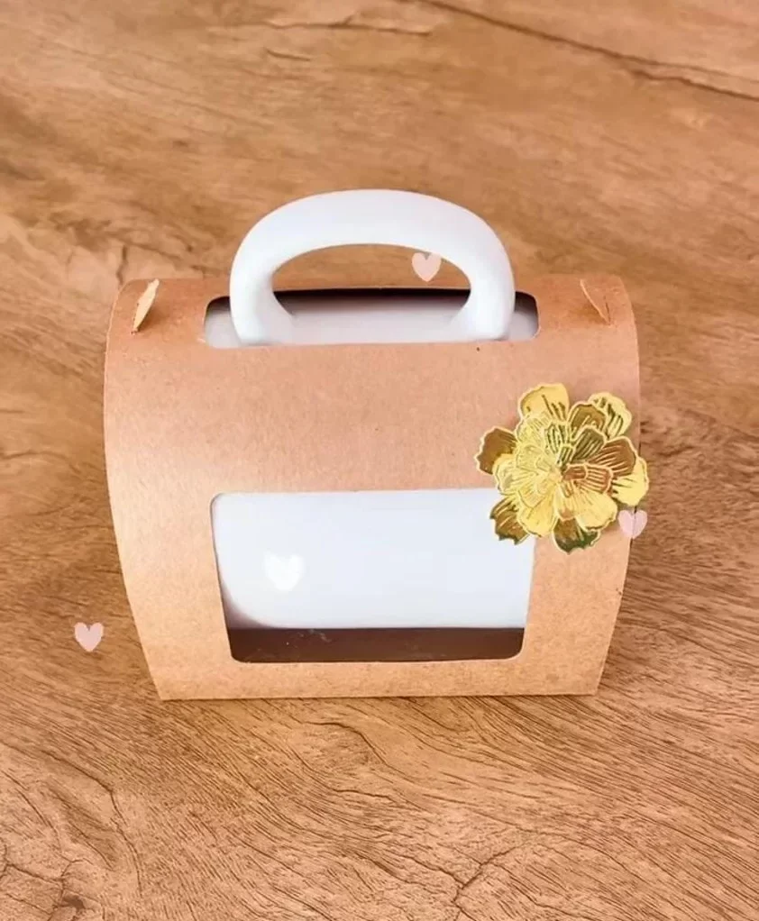 Embalagem de papel tridimensional em formato de bolsa elegante com alças estruturadas, berço interno sob medida para acomodar uma caneca e fecho de encaixe, contendo linhas de vinco pontilhadas em arquivo digital de corte.