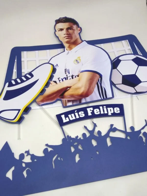 Topper de bolo de futebol com o jogador Cristiano Ronaldo com a camisa número sete comemorando um gol na sua pose clássica de costas, cercado por uma grande bola de futebol realista e estrelas douradas dispostas em camadas tridimensionais em arquivo digital de corte.
