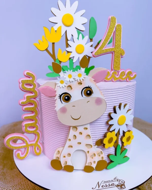 Topper de bolo infantil com uma girafinha filhote sorridente usando uma coroa de flores na cabeça, cercada por grandes flores de papel abertas em tons pastéis e ramos de folhas delicadas dispostos em camadas tridimensionais em arquivo digital de corte.