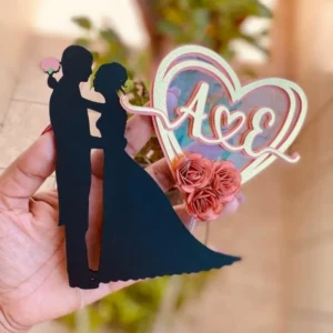 Topper de bolo romântico com a silhueta de um casal apaixonado trocando um beijo sob a luz de uma grande lua cheia decorada com arabescos, cercados por corações flutuantes dispostos em camadas tridimensionais em arquivo digital de corte.