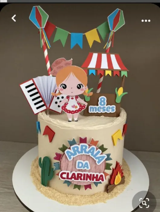 Topper de bolo infantil com uma menina caipira sorridente de vestido de chita colorido e trancinhas, fogueira acesa realista, bandeirinhas juninas penduradas e balão de festa junina em camadas tridimensionais em arquivo digital de corte.