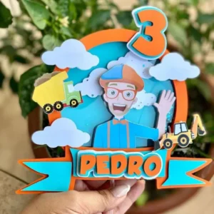Topper de bolo infantil com o personagem Blippi acenando alegremente vestindo seu boné azul e laranja, óculos e gravata borboleta brilhantes, cercado por um trator e estrelas coloridas dispostos em camadas tridimensionais em arquivo digital de corte.