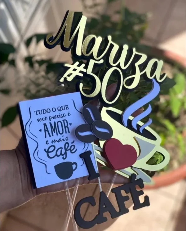 Topper de bolo com uma xícara de café fumegante marrom e branca sobre um pires, cercada por grãos de café torrados em tons de marrom e ramos com folhas e frutos vermelhos dispostos em camadas tridimensionais em arquivo digital de corte.