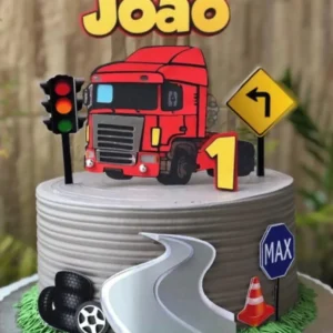 Topper de bolo masculino exibindo um imponente caminhão Scania frontal na cor vermelha brilhante, com detalhes realistas na grade cromada e faróis, cercado por placas de sinalização de rodovia e pneus pretos estruturados em camadas tridimensionais em arquivo digital de corte.