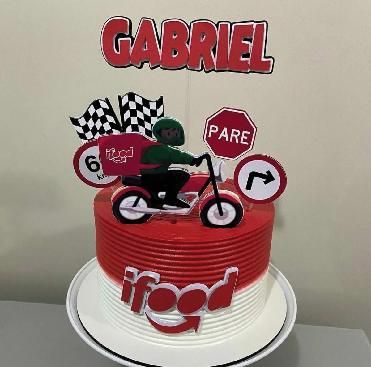 Topper de bolo com a famosa sacola de papel delivery vermelha do iFood com o logotipo branco estampado, uma moto de entregas estilizada, caixas de pizza e hambúrguer flutuando ao redor em camadas tridimensionais em arquivo digital de corte.