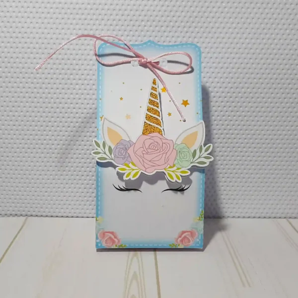 Mockup digital de um topo de bolo montado com o tema Unicórnio, destacando o chifre e orelhas em relevo com apliques de papel dourado e detalhes florais em camadas sobrepostas.