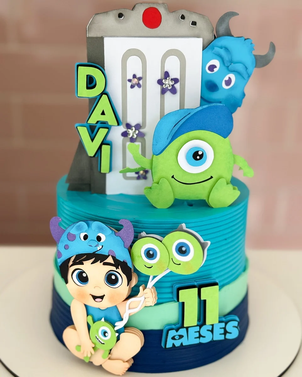 Arquivo de corte digital de topo de bolo do tema Monstros S.A. em formato Studio para Silhouette, mostrando os personagens Sullivan azul e James, o Mike Wazowski verde de um olho só e a pequena Boo ao lado de portas coloridas dispostas em camadas para recorte tridimensional.