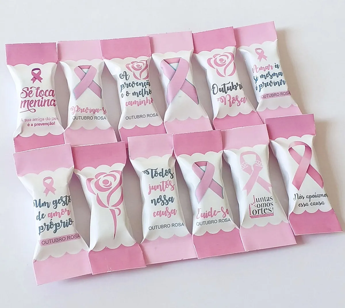 Arquivo digital de embalagens para balas personalizadas no tema Outubro Rosa nos formatos PNG e PDF, exibindo layouts com laços da campanha, frases motivacionais e fundo rosa com elementos florais prontos para imprimir.