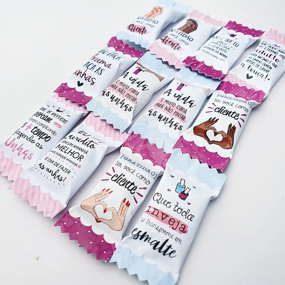 Mockup digital mostrando embalagens de balas impressas e montadas com o tema manicure, decoradas com pequenos corações, esmaltes e fundos florais delicados.