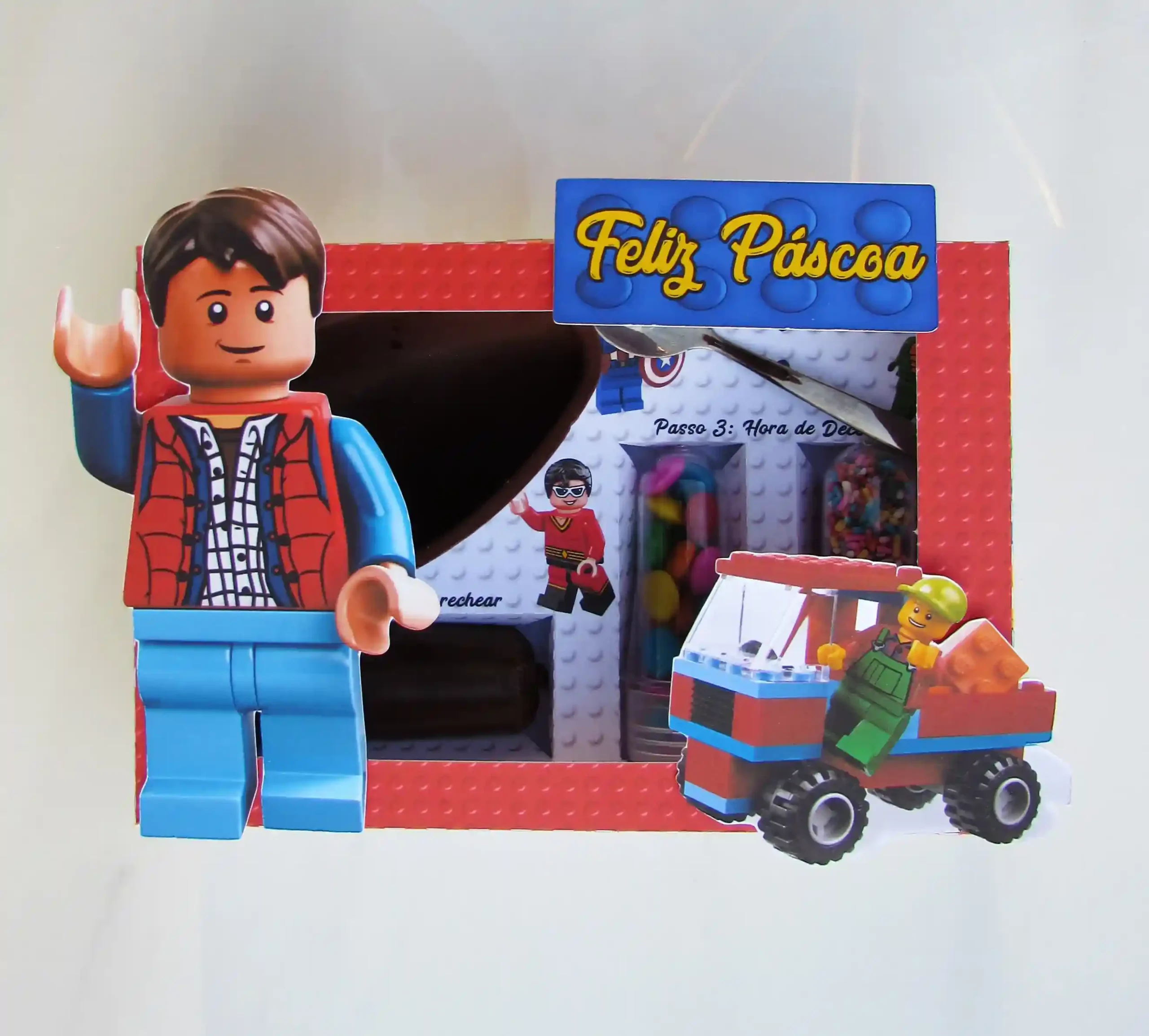 Embalagem interativa de Páscoa com berço para doces decorada com bonecos Lego e peças coloridas em camadas. Arquivo digital em Studio e PDF.