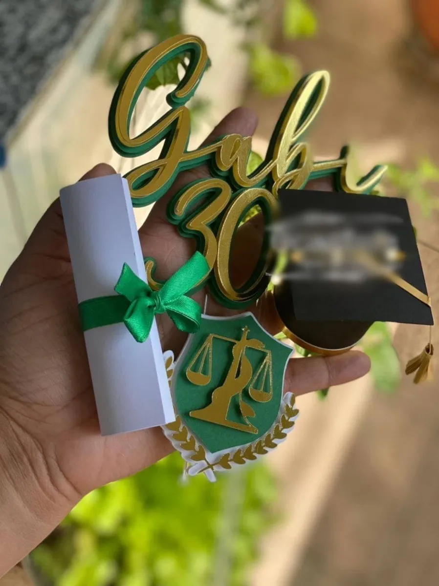 Arquivo de corte digital de topo de bolo para Formatura de Nutrição em formato Studio para Silhouette, mostrando o símbolo da nutrição com a balança e a serpente, um capelo de formatura, diploma amarrado com fita verde e elementos florais dispostos em camadas prontas para recorte tridimensional.