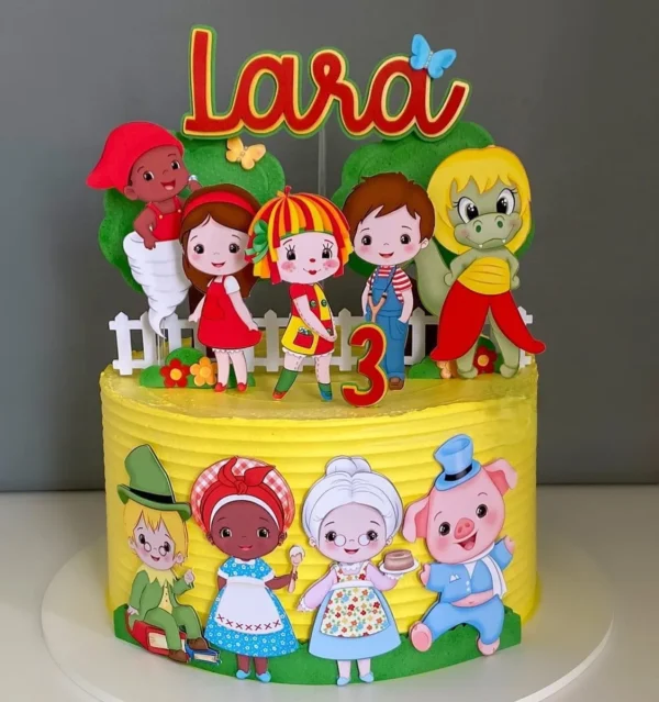 Arquivo de corte digital de topo de bolo do tema Sítio do Picapau Amarelo em formato Studio para Silhouette, mostrando a boneca Emília, o Visconde de Sabugosa, o Pedrinho e a Narizinho ao lado de árvores frutíferas e cercas rústicas em camadas para recorte tridimensional.